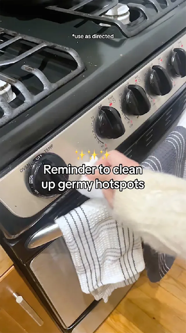 Hand wiping control knob of stove with caption, "Reminder to clean up germy hotspots."