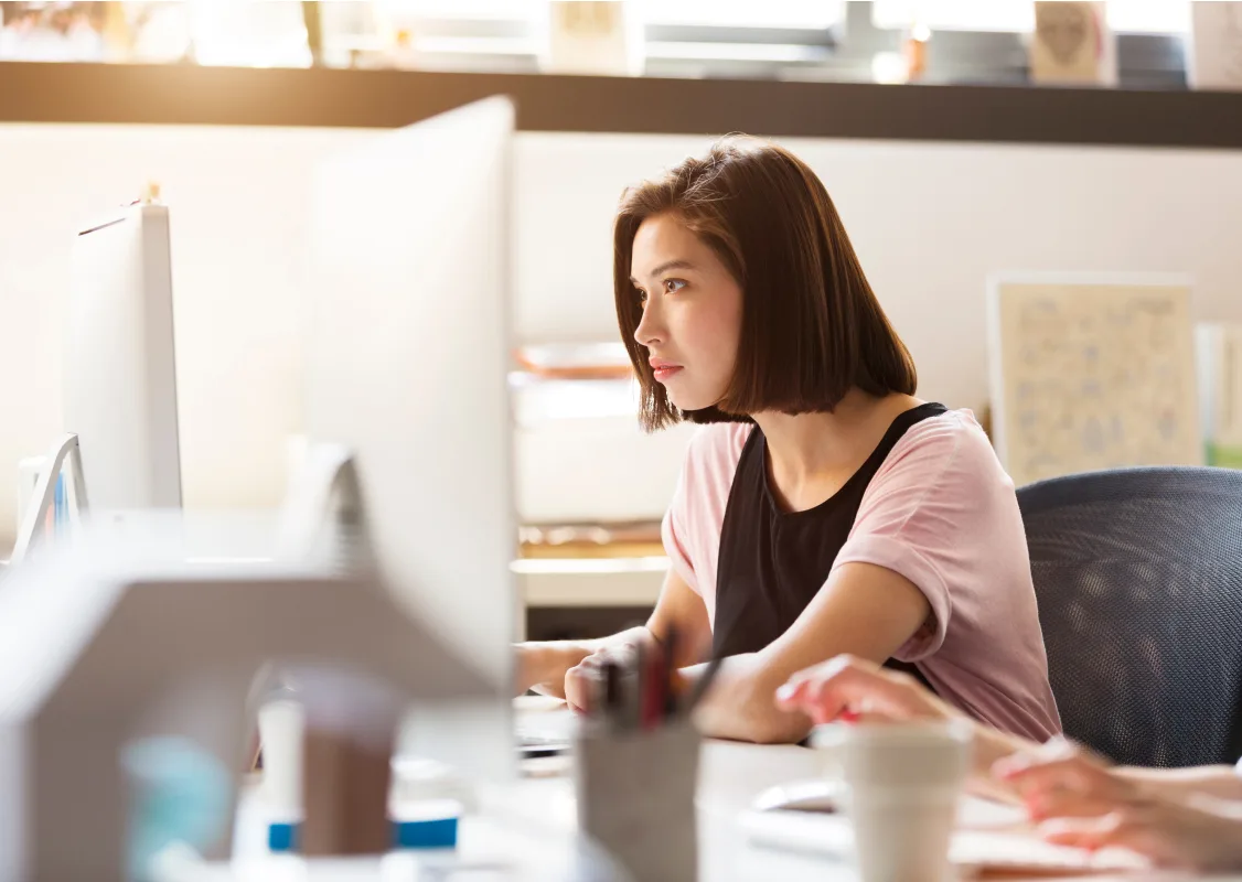 woman working at her desk, looking at a computer monitor