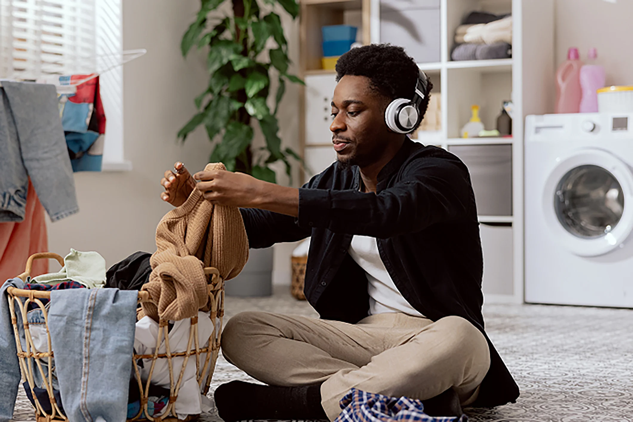 Person with headphones on, sitting on the floor folding laundry