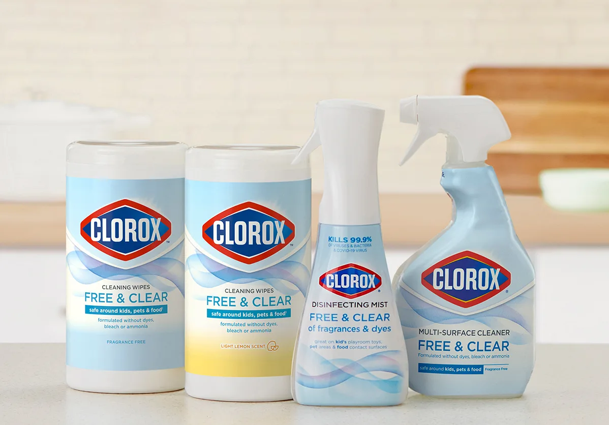 Four cleaning products showing Clorox label and blue wave design on a clean kitchen counter with blurred tile background.