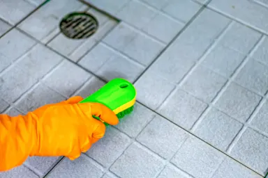 Person cleaning floor tile grout.