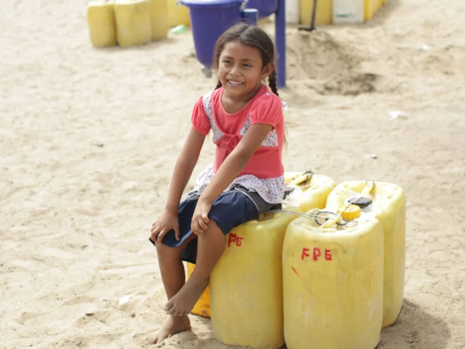 niña sentada en contenedores de agua