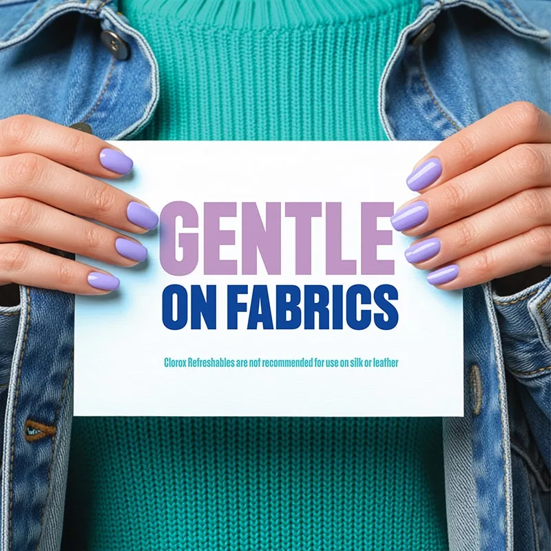 A person with nails painted purple, holding a sign that says "Gentle on Fabrics"