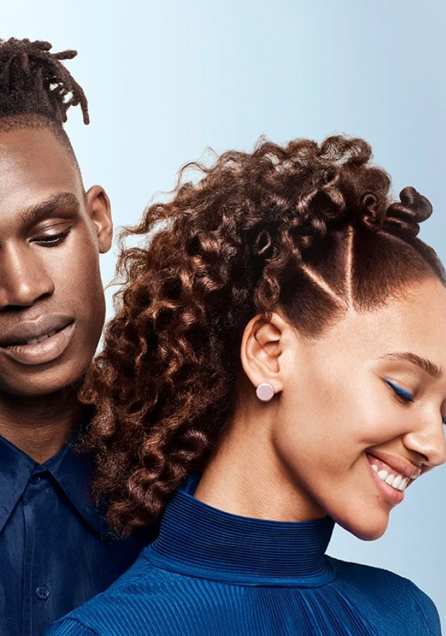 Boy and girl with curly hair smiling - a boy is standing behind a girl. 