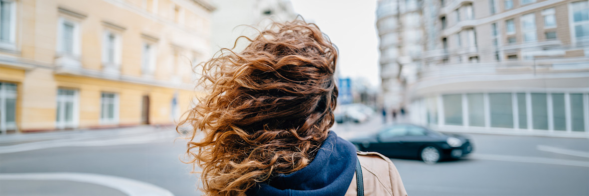 A close-up of long, wavy brown curly hair showing rich texture and volume.