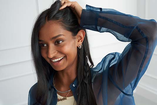 a woman smiles and detangles her long hair