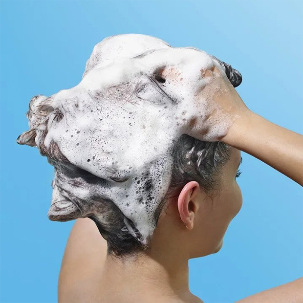 A woman washing her hair standing backwards - a view on her head.