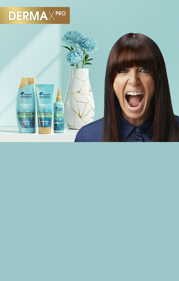 Claudia Winkleman on the right, screaming, on her left a vase with flowers and 3 H&S Derma X Pro products in the background