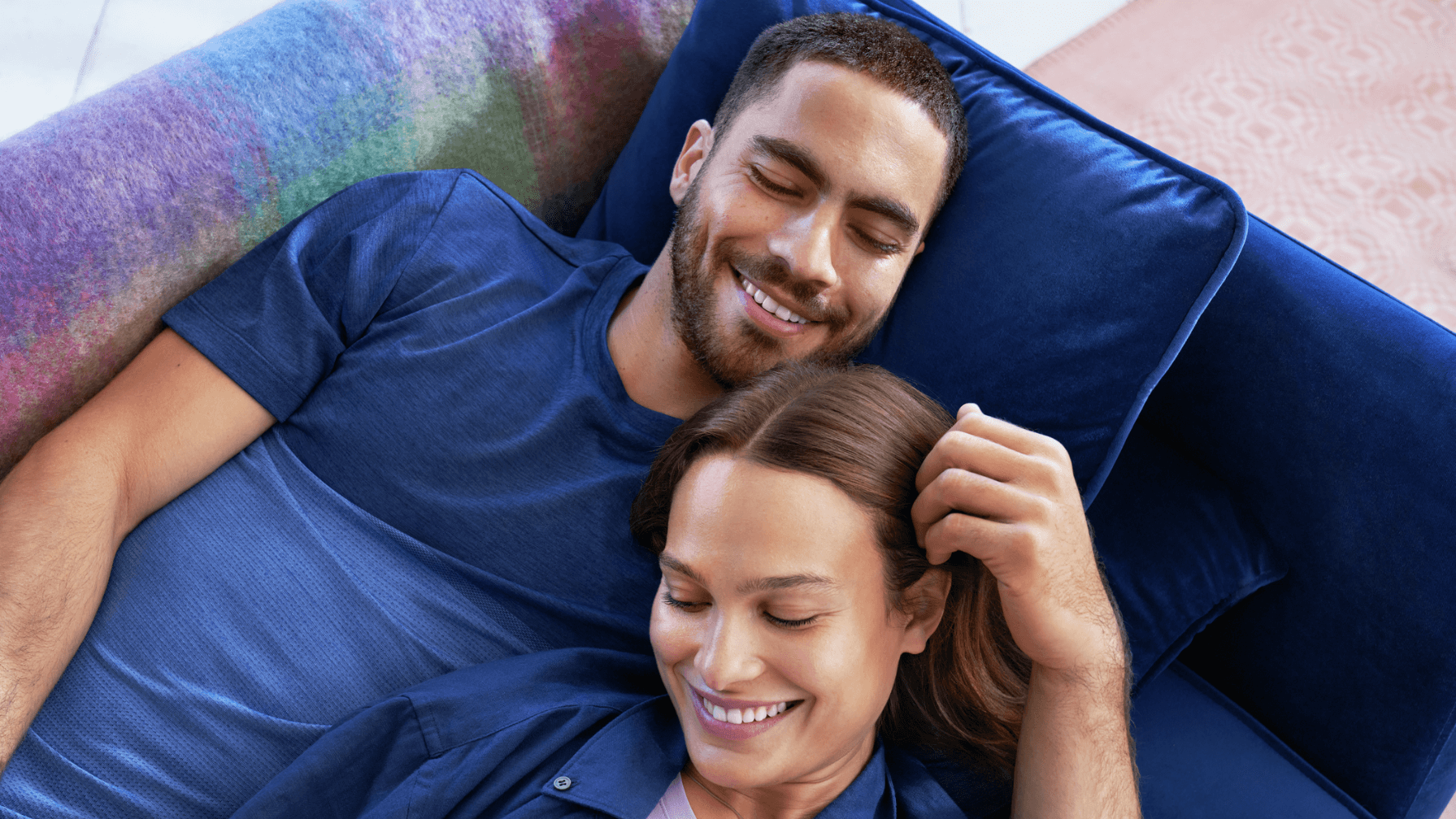 Man and woman, lying down on the couch, both smiling