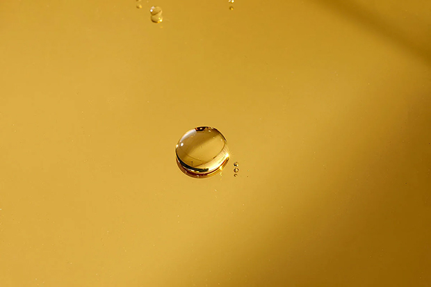 Oil drop on plain mustard-coloured surface.