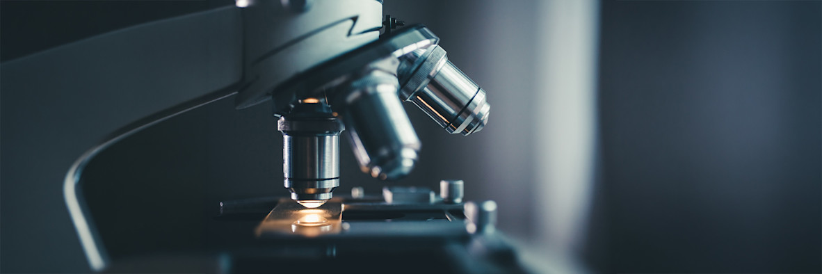 A professional microscope in a laboratory setting against a dark background.