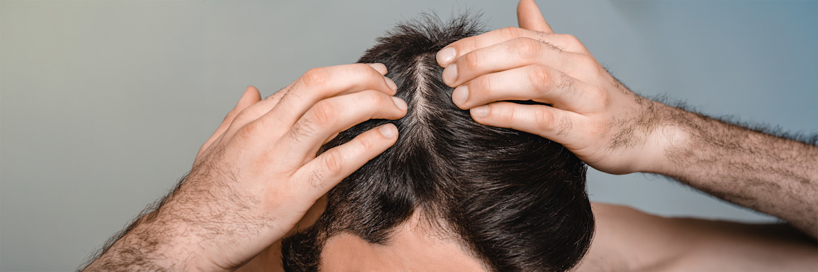 Two hands massage shampoo or a scalp treatment into wet hair from above.