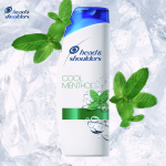 Menthol Fresh Shampoo bottle on the ice background and mint leaves on sides of the bottle.