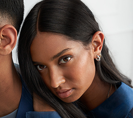 Young woman with long dark hair resting her head on the man's back. 