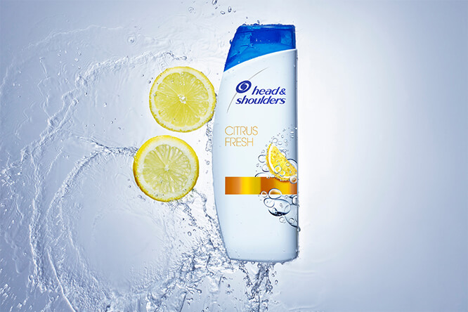 Citrus Fresh Shampoo with water splash in the background and citrus slides on the bottle side.
