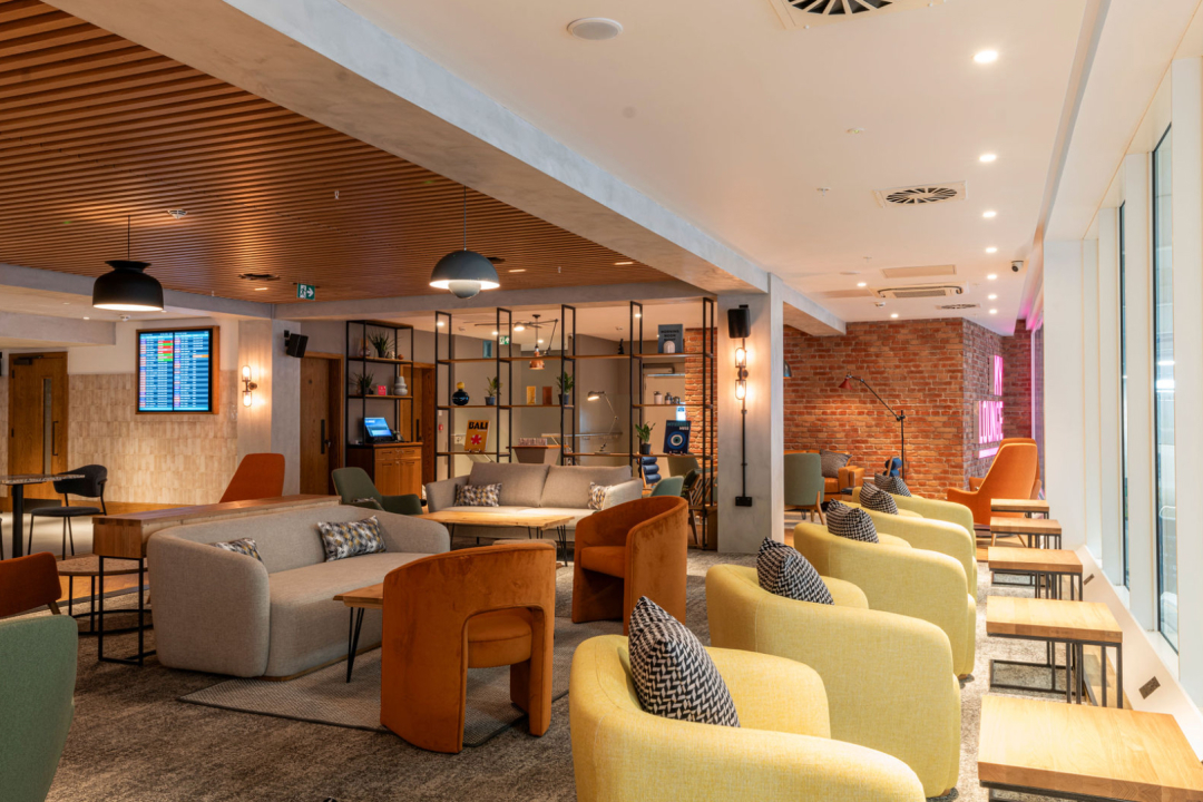 Airport lounge, yellow seats, grey sofa, large open space 