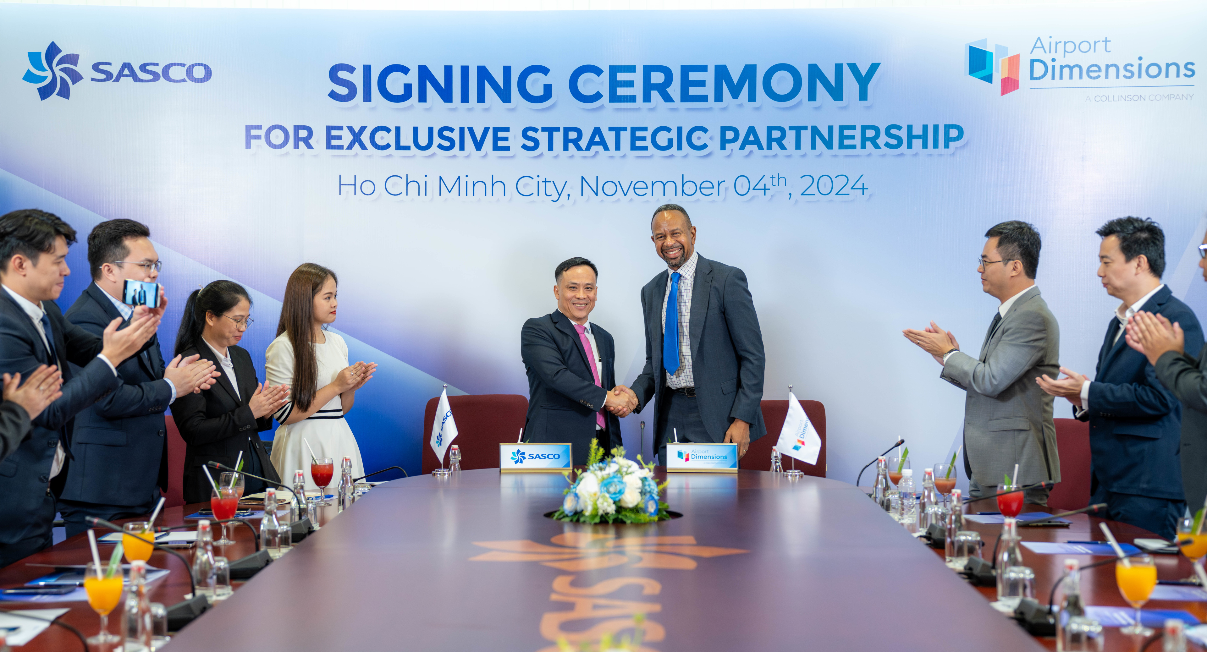 Group of men and women standing around table at signing event 