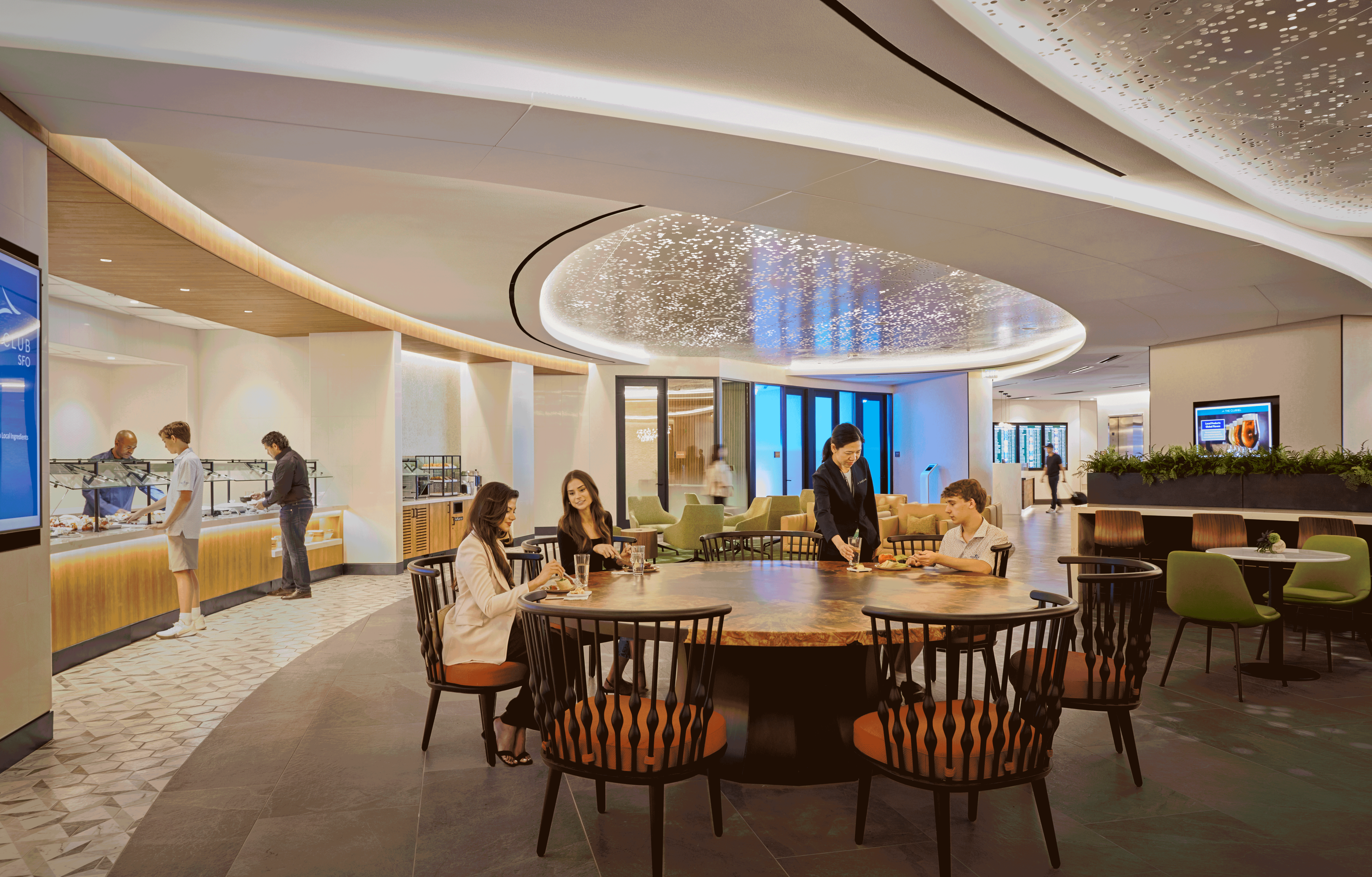 airport lounge, round table with two women and one man sitting, waitress placing down glass