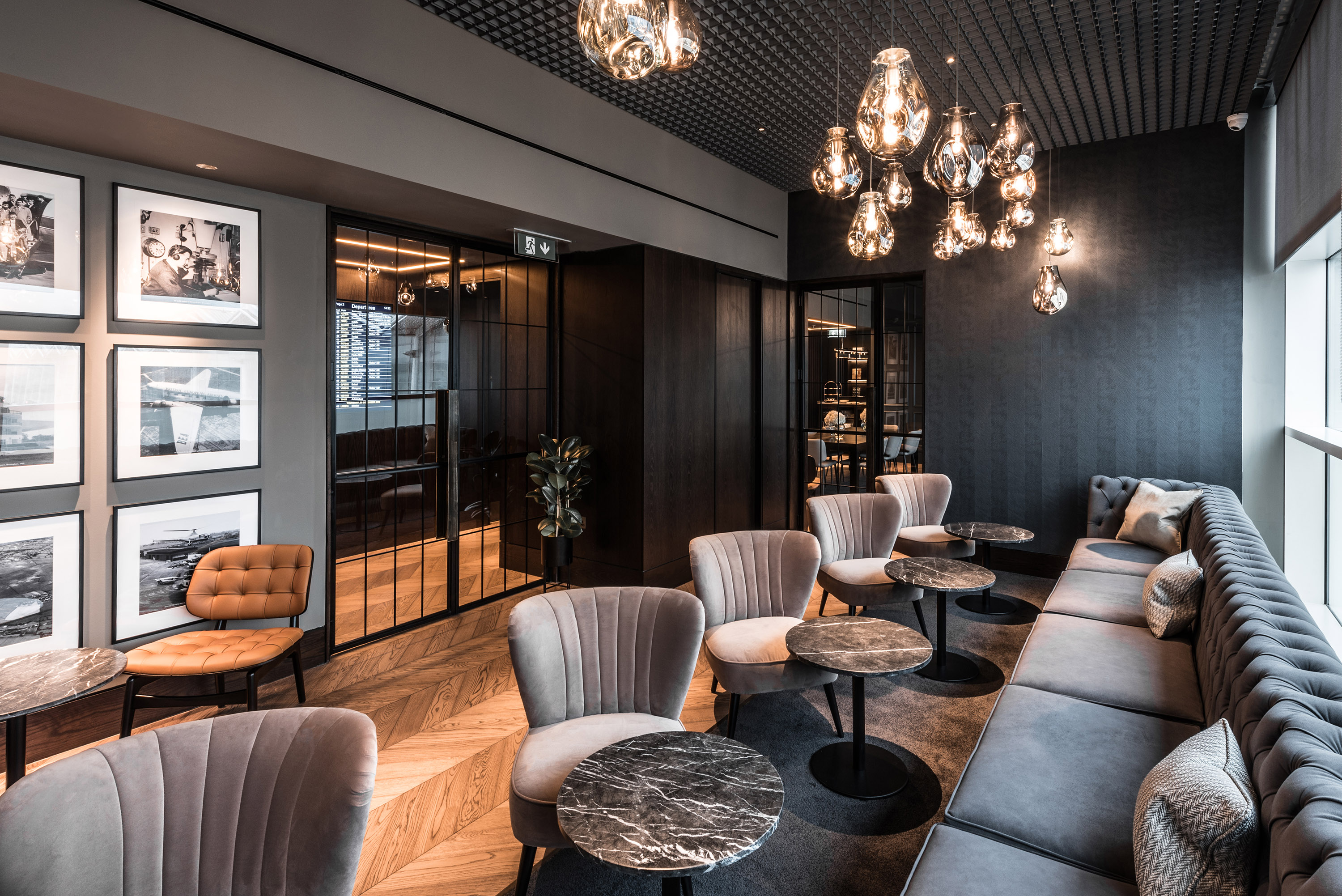 airport lounge, grey benches, chairs and tables, picture frames on wall