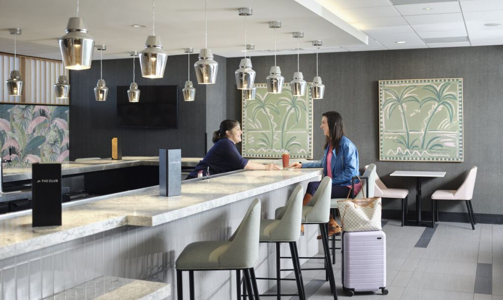 The Club airport lounges bar area with staff member and guest 