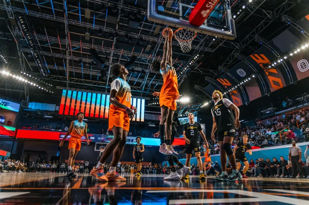 A basketball player making a slam dunk on an indoor court full of spectators