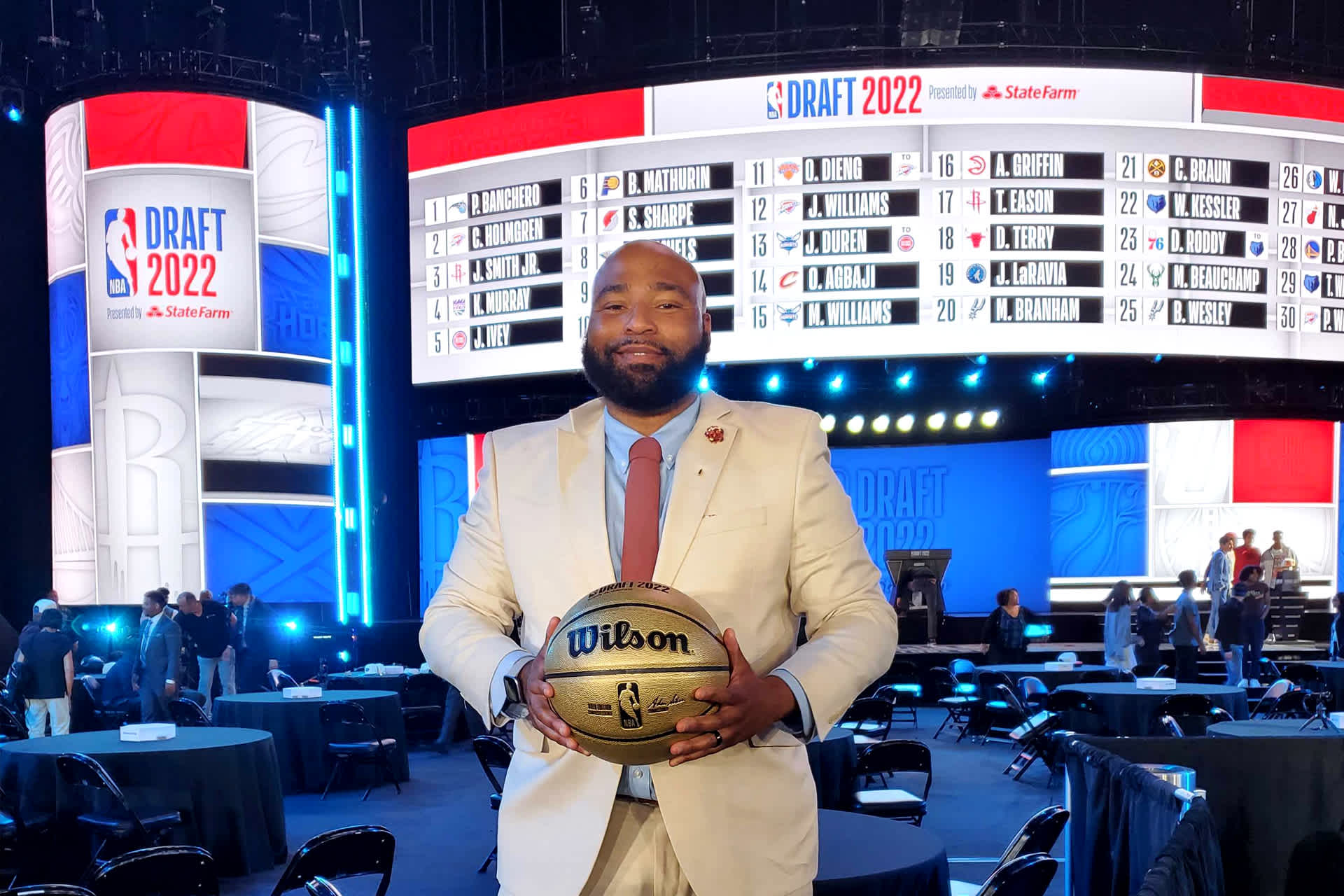 Bransford in white suit, holding a basketball