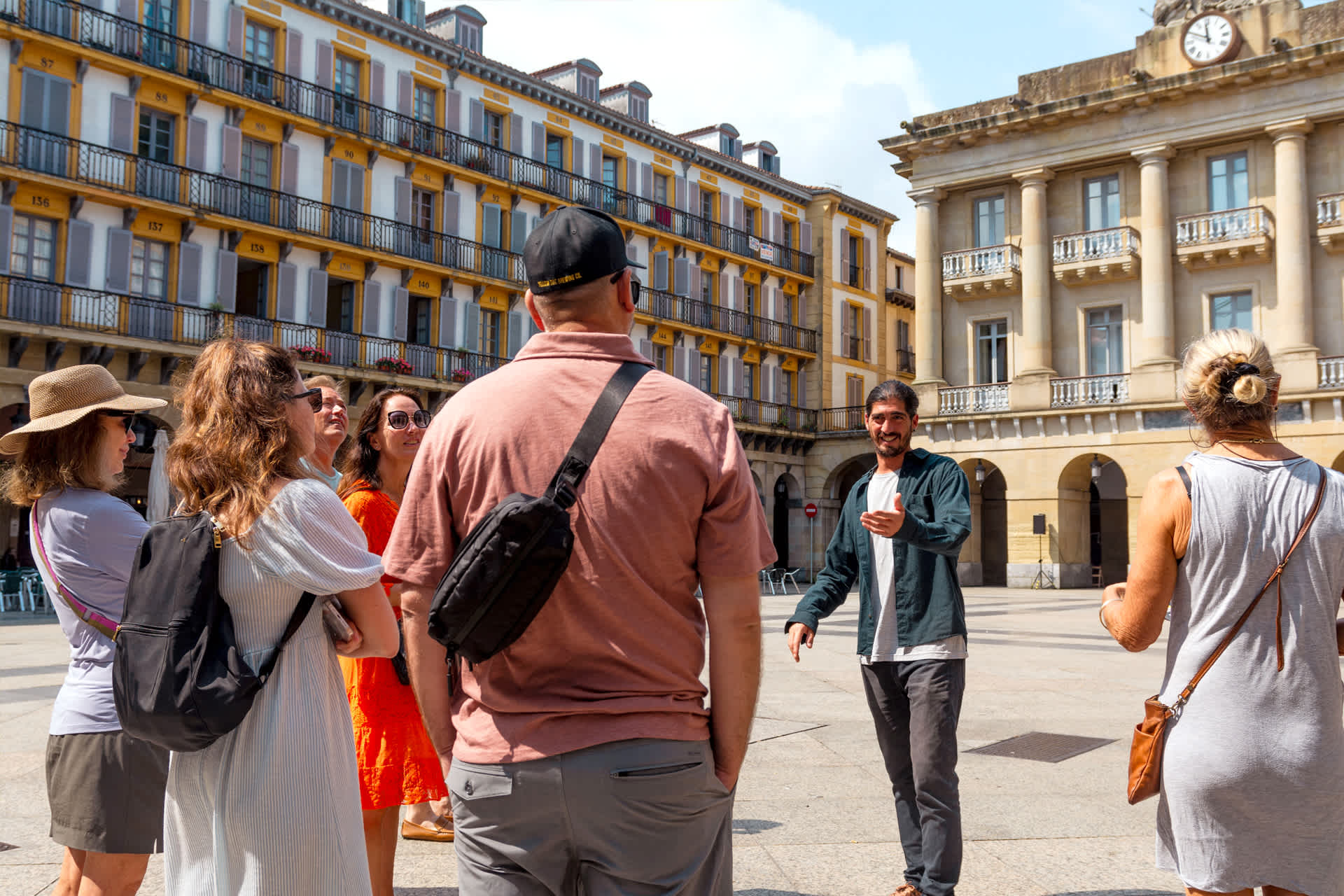 A group of people standing in a plaza listening to a tour guide