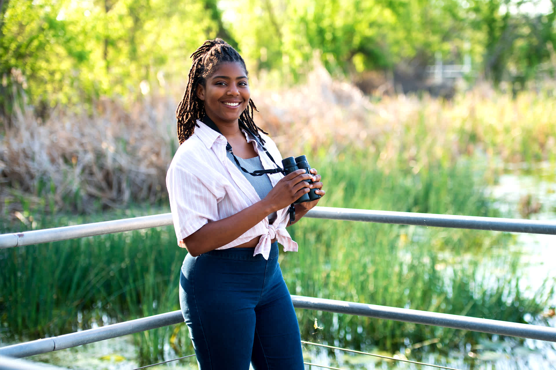 Image: Danielle Belleny standing outdoors, holding binoculars