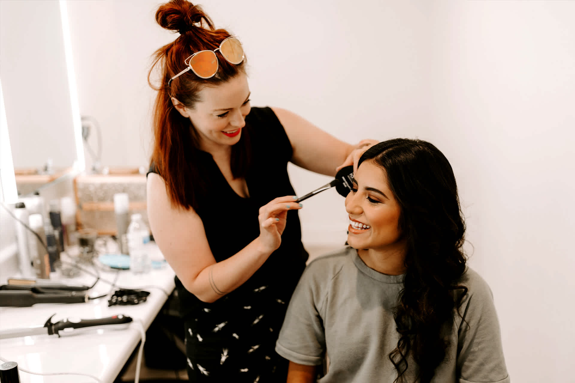 A makeup artist applies a product using a brush to a client's face