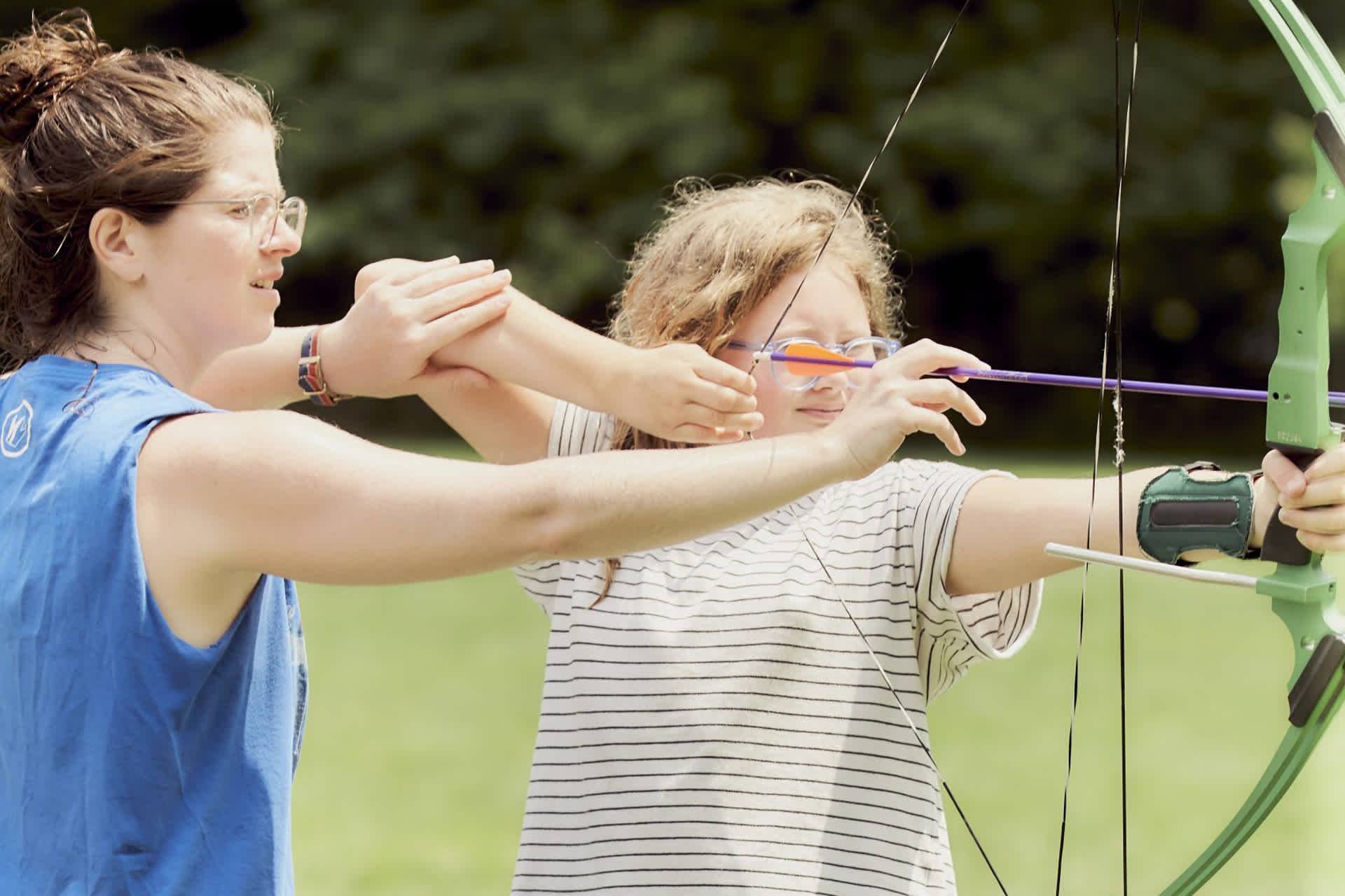 A woman coaches a young archery student.