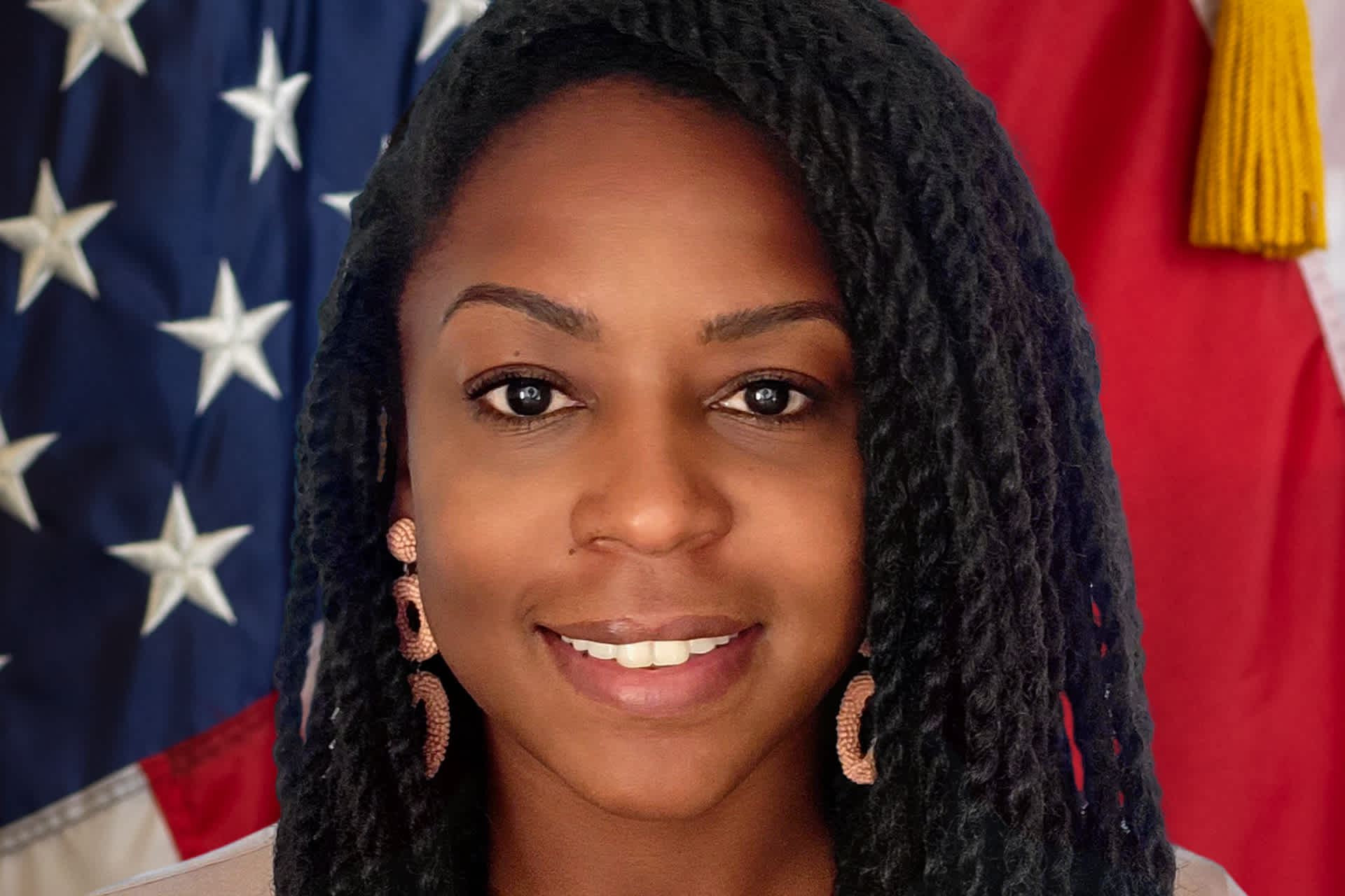 Photo of a Black woman with long hair posing against the American flag
