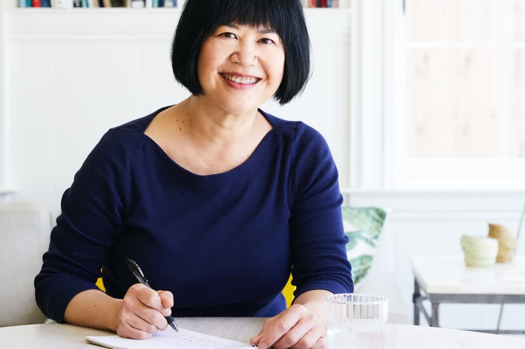 Food writer Andrea Nguyen smiling and writing in a notebook.