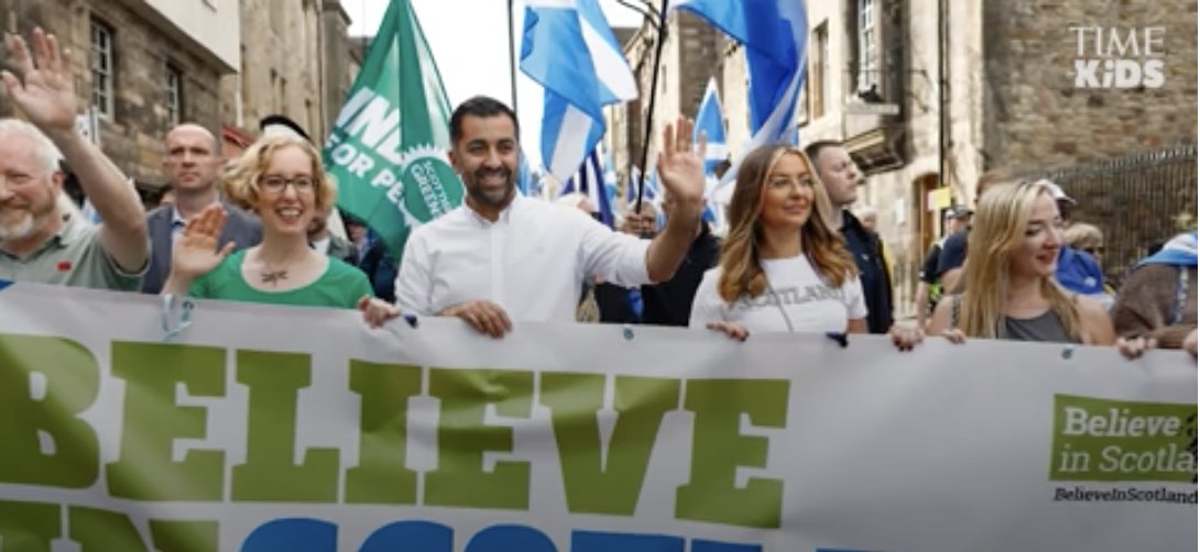Group of people holding "Believe in Scotland" banner and waving