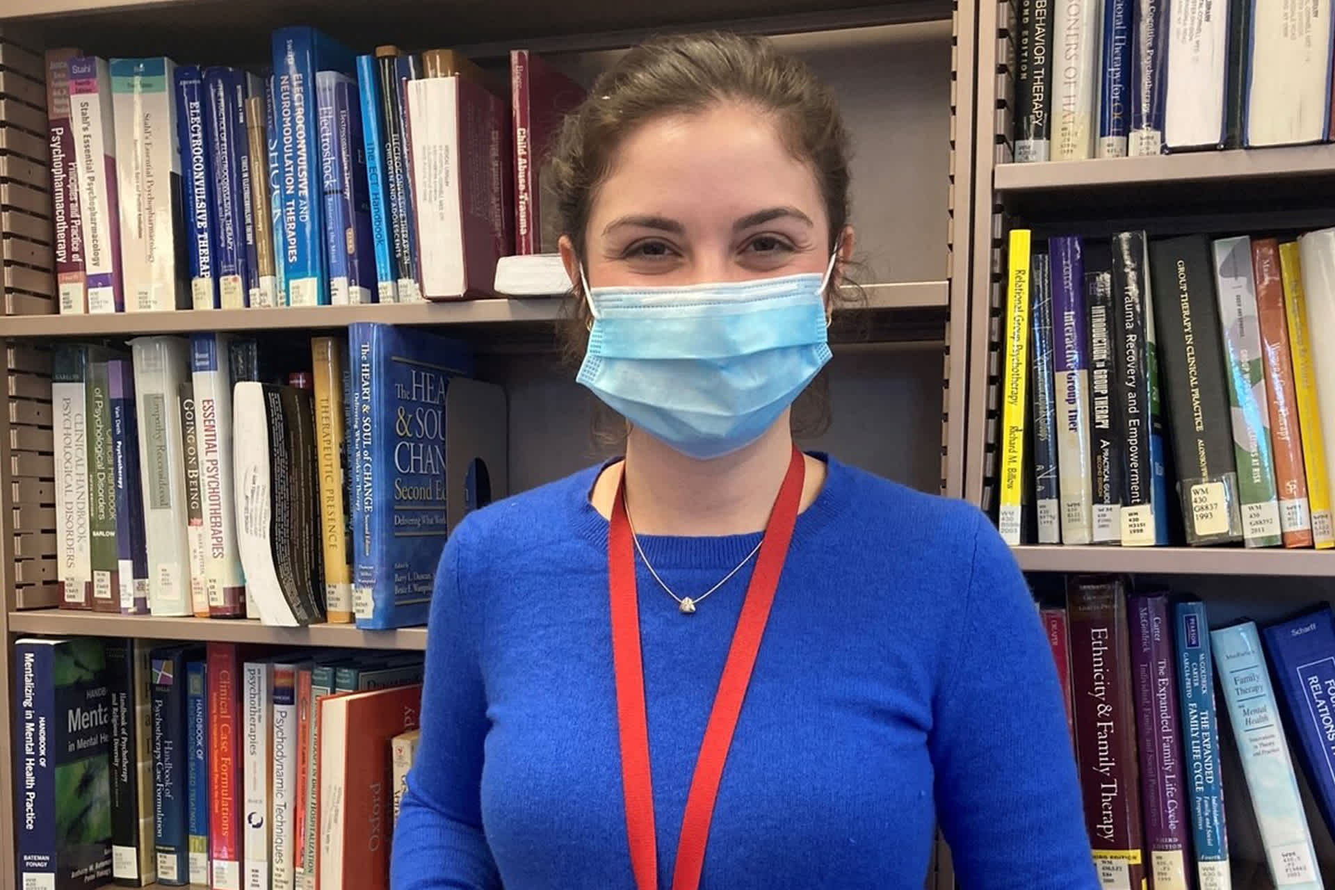 a librarian in a mask stands in front of books