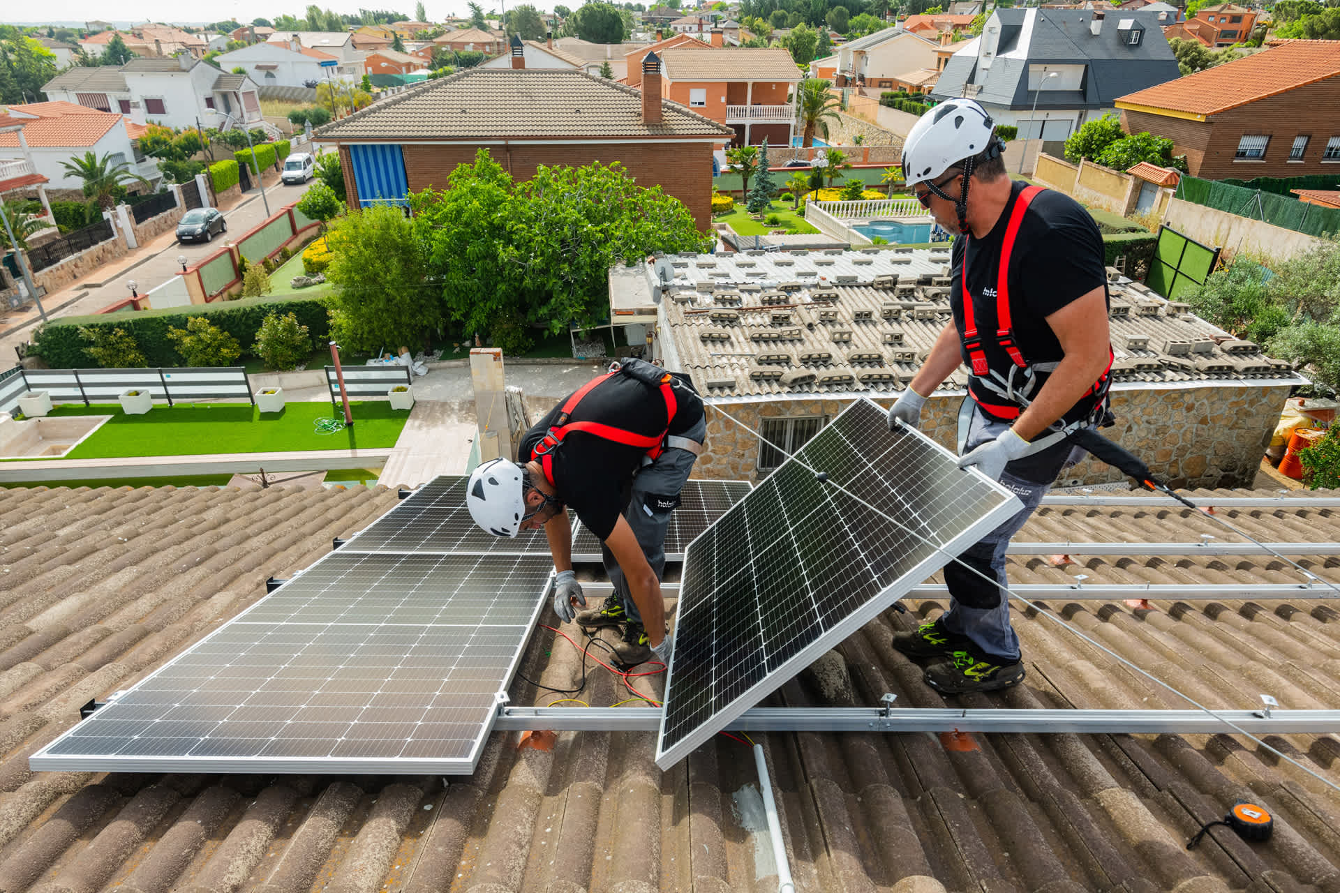 A duo of engineers installing solar panels on the roof of a residence in Spain.