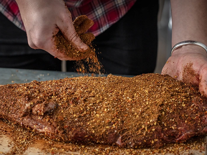 A brisket being seasoned