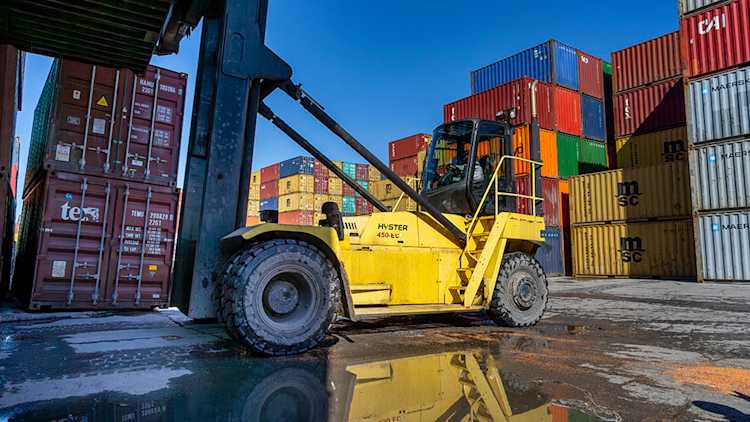 Forklift with shipping containers in background.
