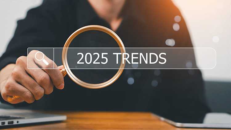 Person looks through magnifying glass at ‘2025 trends’.