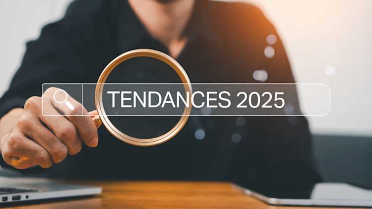 Une personne regarde à travers une loupe les « tendances de 2025 ».