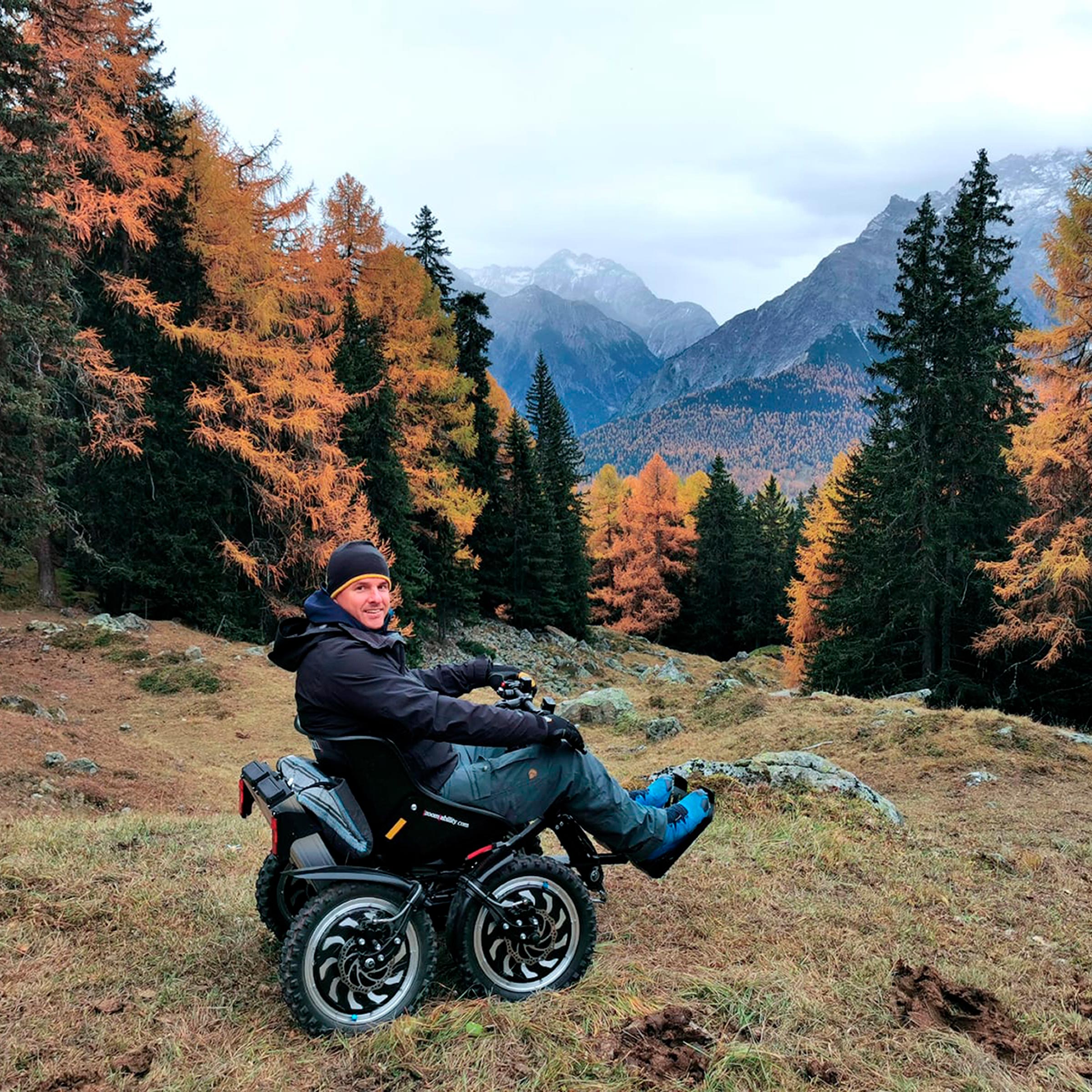 Un utente sorride a bordo del suo fuoristrada elettrico zoom davanti al panorama delle montagne