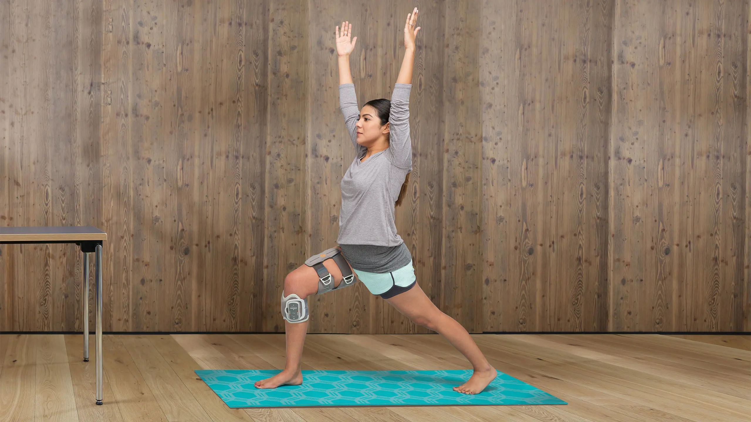 Una ragazza pratica yoga sul suo tappetino mentre indossa l'elettrostimolatore con cosciale L300 Go Plus Upgrade