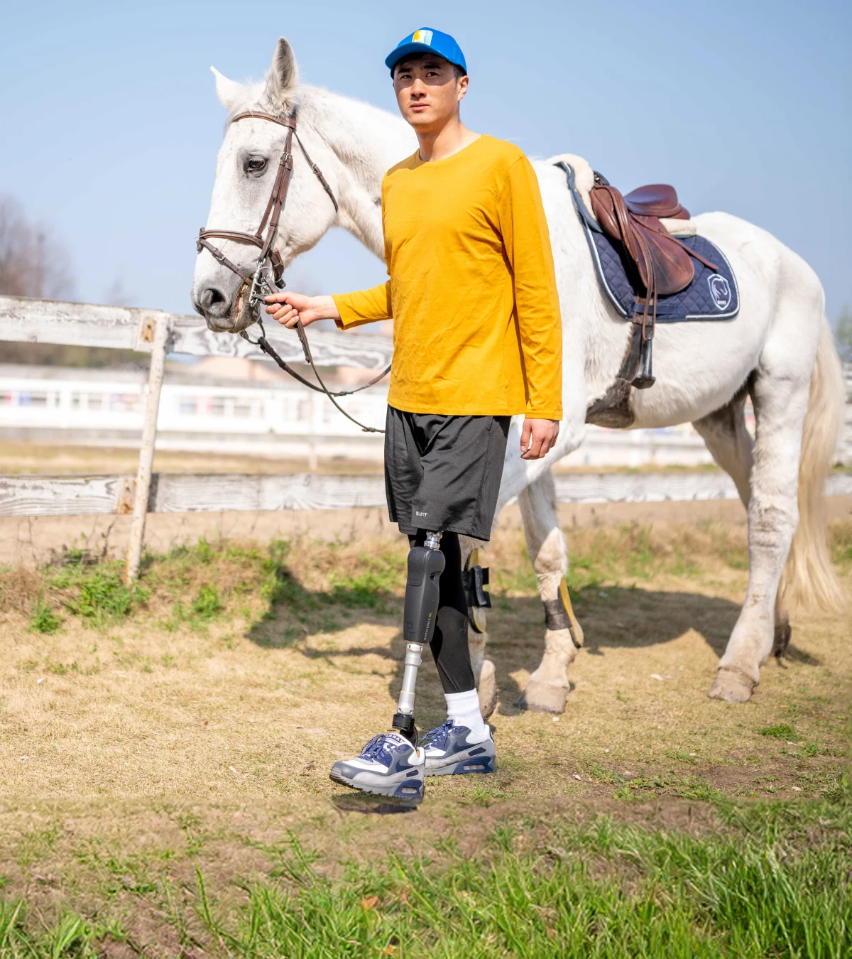 Un usuario de pierna protésica de la extremidad inferior caminando afuera con su caballo 