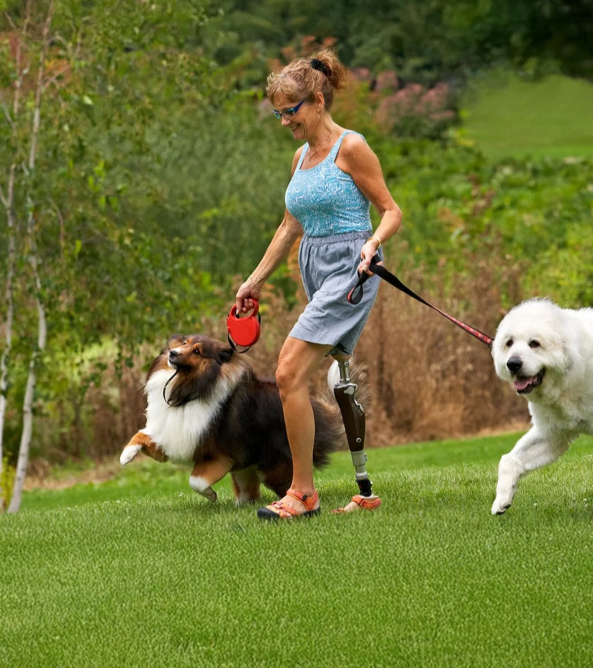 Un usuario de pierna protésica paseando a sus perros en un campo al aire libre