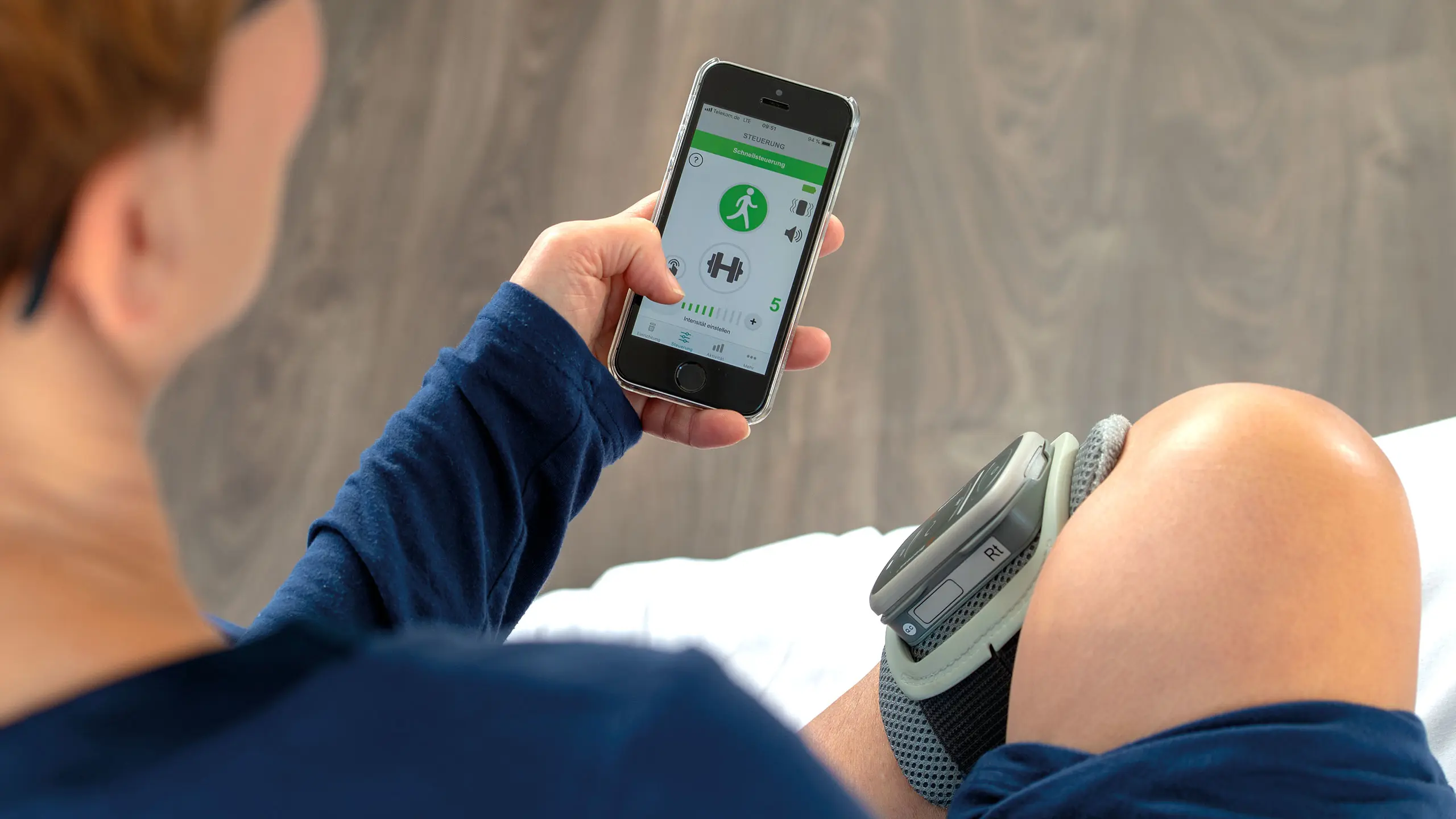 Un paziente con L300 Go tiene in mano lo smartphone con l'app per controllare il dispositivo