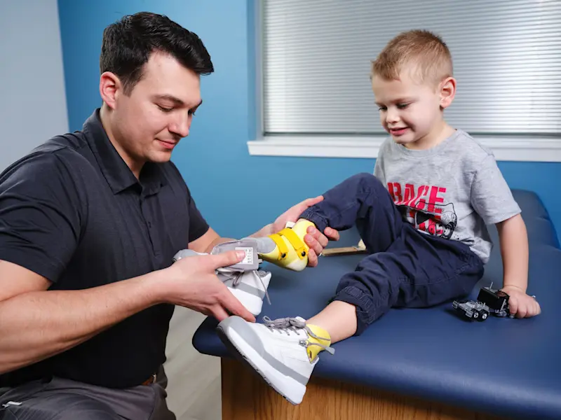 A Certified Prosthetist Orthotist helping a pediatric patient with orthotic shoes