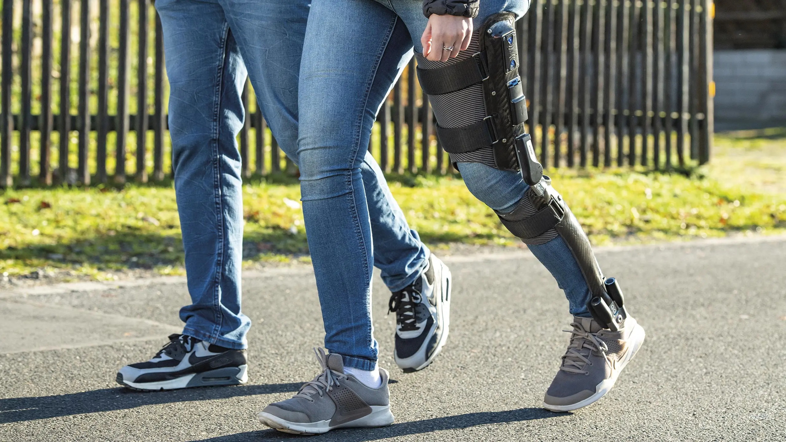 Dettaglio di un paziente che cammina in esterno con l'ortesi E-Mag Active sopra i pantaloni jeans