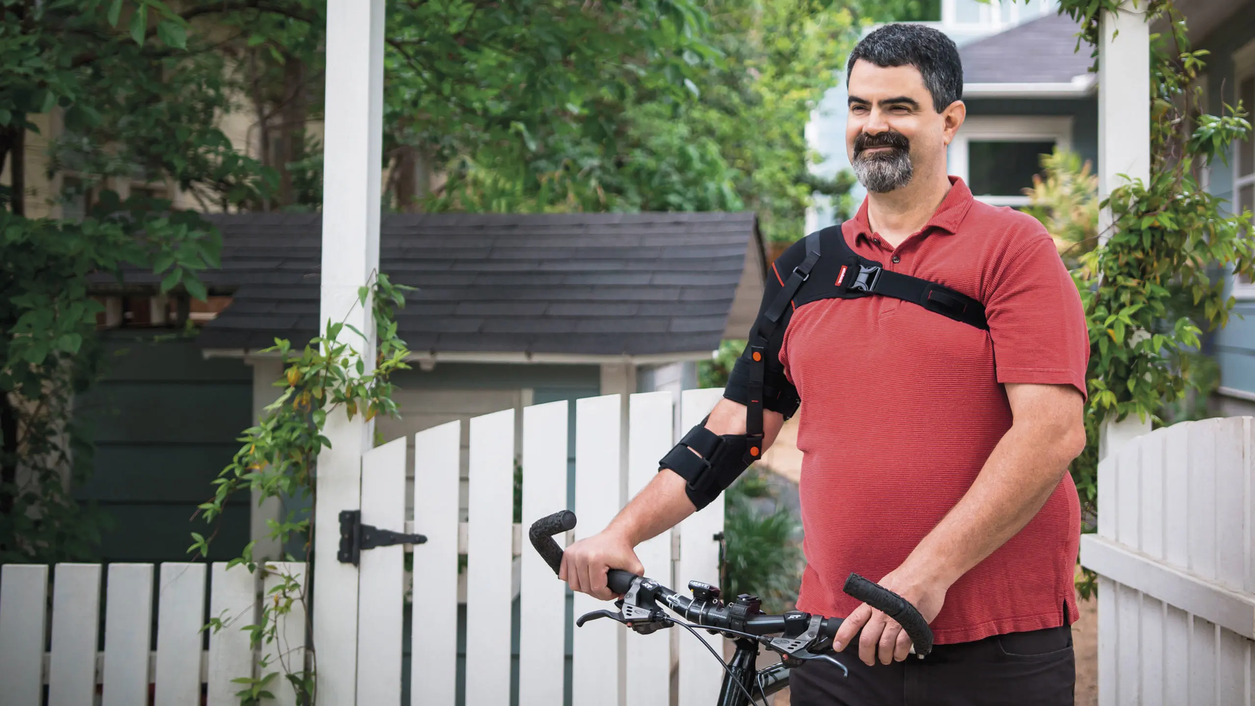 Una paziente con l'ortesi Omo Neurexa Plus indossata sulla spalla accompagna a mano la bicicletta