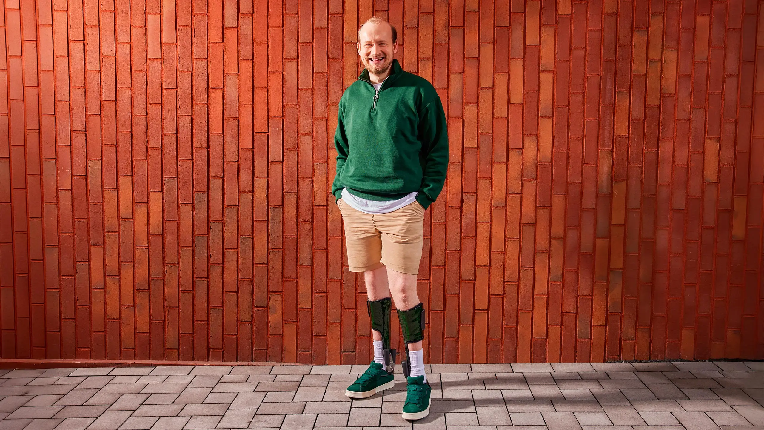 Un paziente posa davanti a un muro di mattoni rossi mentre indossa la sua ortesi Nexgear Tango