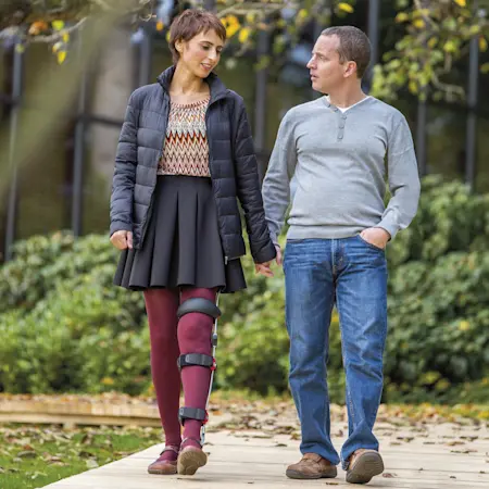 Una paziente con l'ortesi FreeWalk sulla gamba sinistra passeggia mano nella mano con il compagno