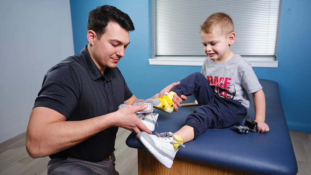 Un Ortocista Certificado (OC) colocando un zapato ortésico en un paciente pediátrico